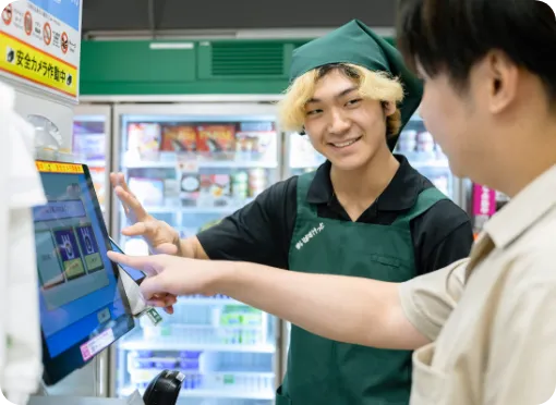 学生スタッフのM.K.さんがセルフレジの操作方法を教えている様子